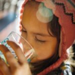 Child sipping on water from a cup.